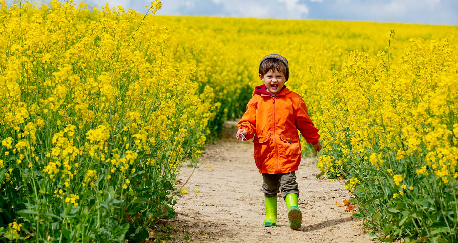 Happy kid running in rapeseed field in spring